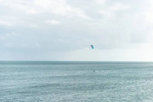 Man surfing, kitesurfing with kite on board in Florida at ocean, sea in distance far away in Bahia Honda Key Keys