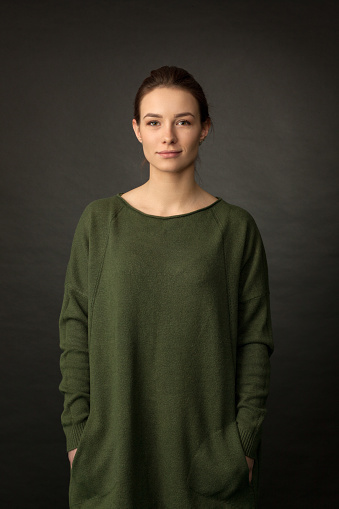 Studio portrait of a 20 year old attractive woman in a green sweater on a black background