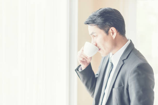istock Side View Of Businessman Drinking Coffee While Standing By Window At Home 1081712526