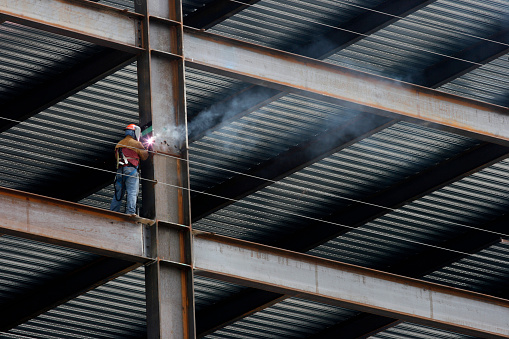 Construction Worker Welding Beam on High Rise Building