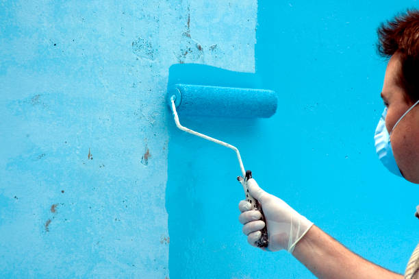 Painter wearing face mask while painting a wall bright blue
