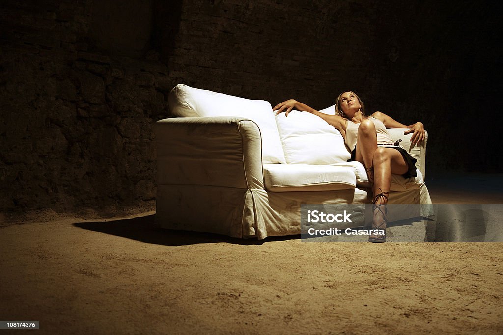 Jeune femme assise sur un canapé dans l'espace A l'abandon - Photo de 20-24 ans libre de droits