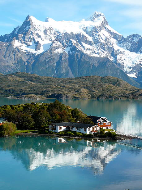 Wooden pathway with snowy Towers of Paine and Paine Horns beneath clouds in background, springtime in Patagonia.