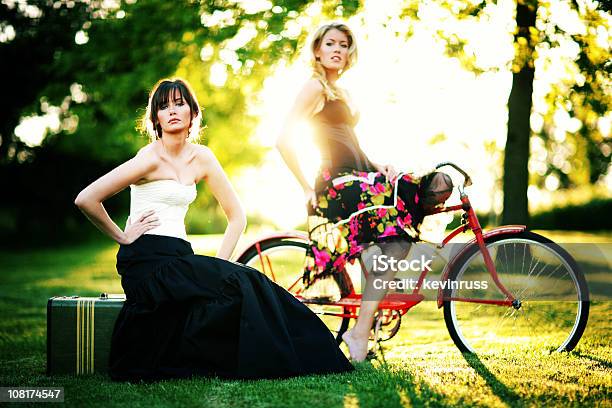 Two Females With Old Suitcase And Red Bike Stock Photo - Download Image Now - Adult, Adults Only, Beautiful People