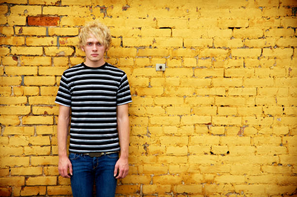 istock Teenage Boy Standing Against Yellow Brick Wall 108174716
