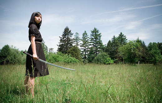 Young Asian woman with katana blade.  Horizontal with copy space.