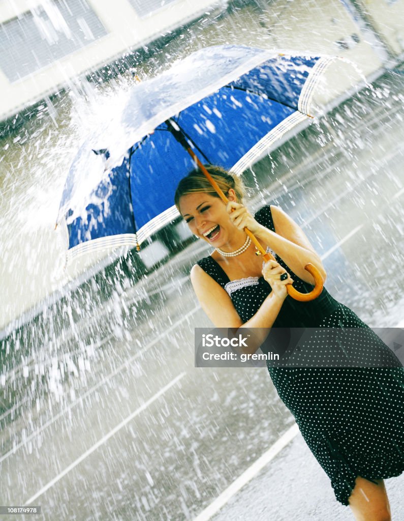 Joven mujer sosteniendo paraguas durante la caída de lluvia - Foto de stock de Lluvia libre de derechos