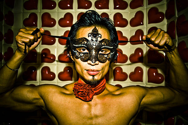 Torse nu homme asiatique à nouer sur un masque contre coeur fond - Photo
