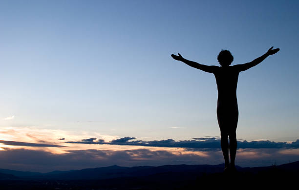 silhouette der mann mit ausgestreckten armen in richtung himmel bei sonnenuntergang - yoga nudist silhouette naked stock-fotos und bilder