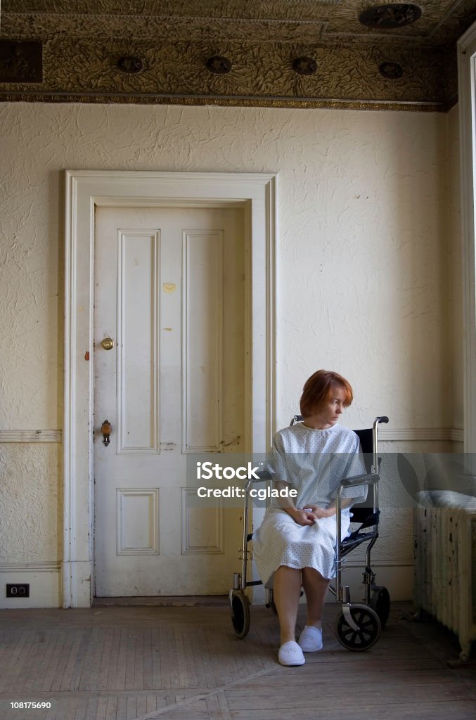 Woman Sitting on Wheelchair in Empty, Grunge Room  40-49 Years Stock Photo