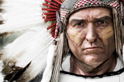 Horizontal portrait of a Native American Chief wearing a feathered head dress.