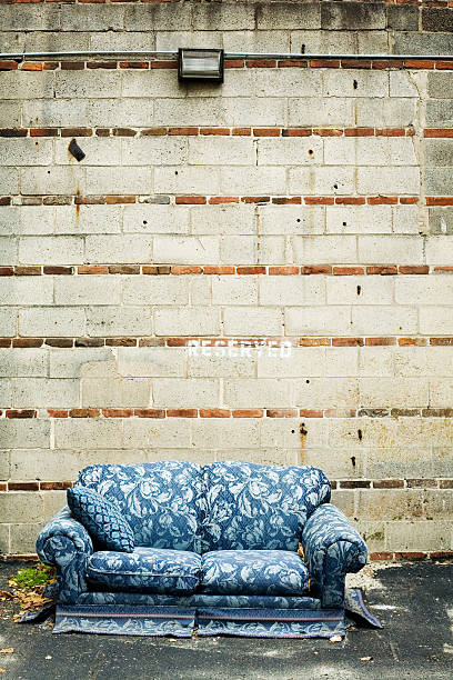 Abandoned Blue Couch Sitting Against Cement Wall Outside stock photo