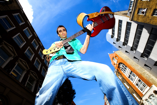 Male young adult jumping and playing an electric guitar isolated on white background