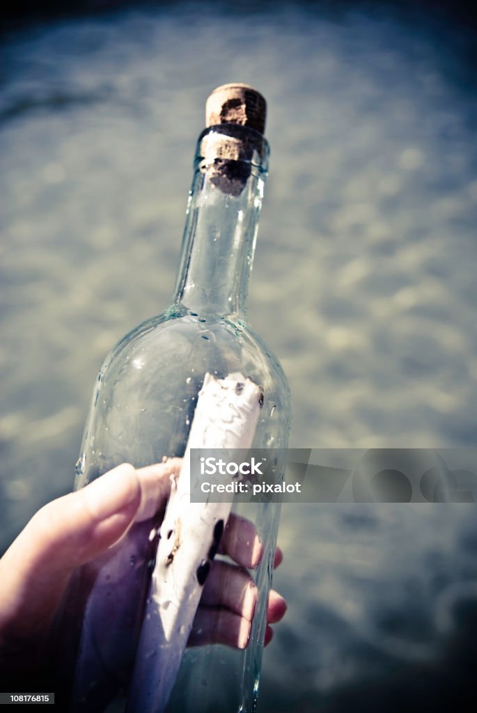 Mano agarrando mensaje en una botella - Foto de stock de Mensaje en una botella libre de derechos