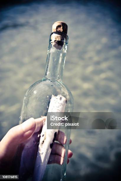 Mano Agarrando Mensaje En Una Botella Foto de stock y más banco de imágenes de Mensaje en una botella - Mensaje en una botella, Agarrar, Aire libre