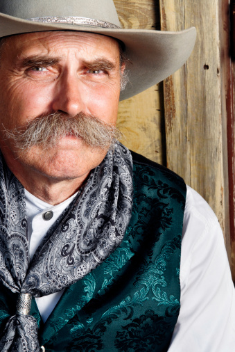 Close-up portrait of a cowboy looking on camera.