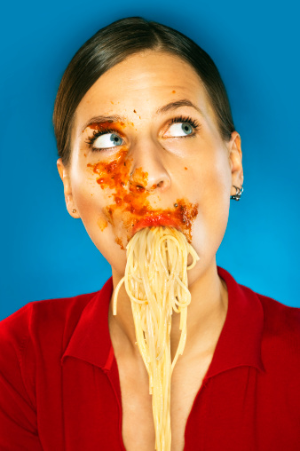 pretty girl with tomato sauce all over her face sucking noodles