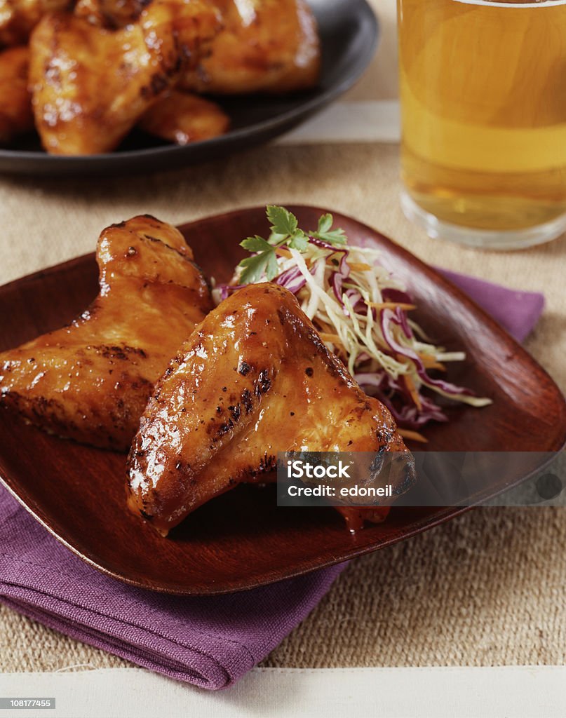 Ailes de poulet sur une assiette avec de la bière en arrière-plan - Photo de Aile de poulet libre de droits