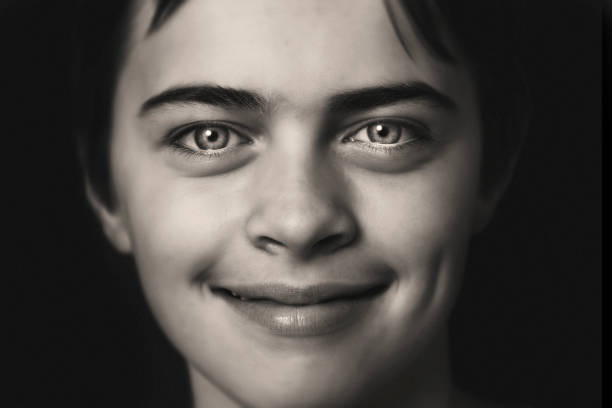 Teenager smiling at camera on a black background.