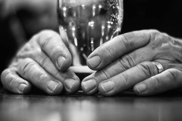 Elderly Man's Hands Holding Pint Glass.