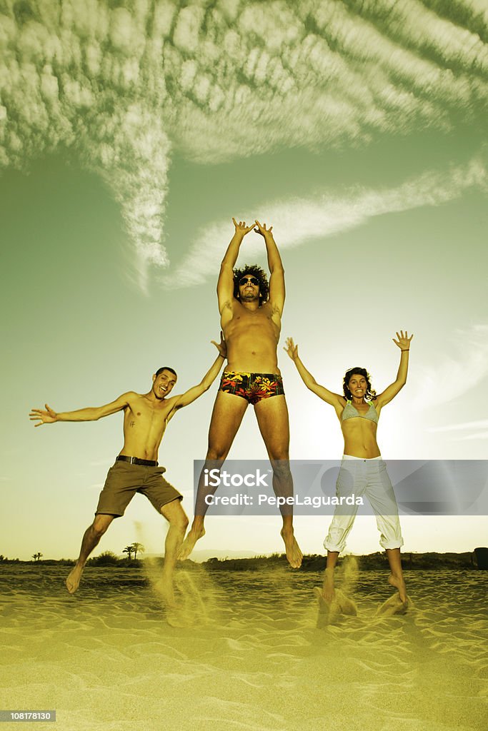 Trois heureux jeunes de sauter sur la plage - Photo de Activité libre de droits