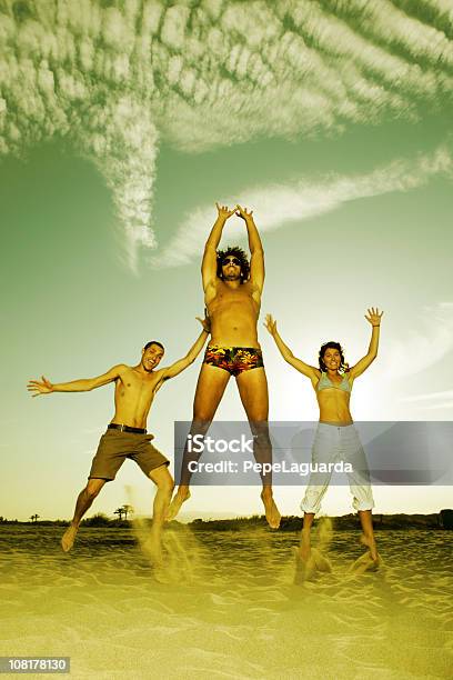 Photo libre de droit de Trois Heureux Jeunes De Sauter Sur La Plage banque d'images et plus d'images libres de droit de Activité - Activité, Adulte, Amitié