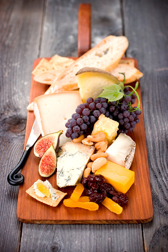 A delicious selection of fine imported cheeses served with fruit, nuts, bread and crackers.  shallow dof.