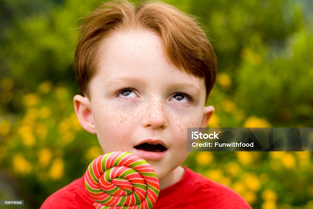 Boy Pelirrojo peca cara niño con Piruleta; Caramelos girar los ojos - Foto de stock de Aburrimiento libre de derechos