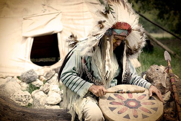 Native American Chief Playing Drum Outside Teepee stock photo