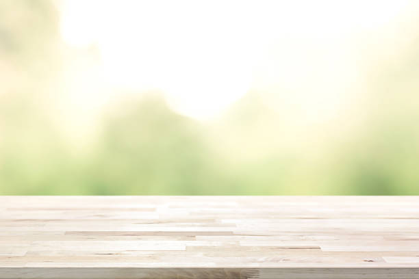 istock Wood table top on bright sunlight and blur green tree background 1081783400
