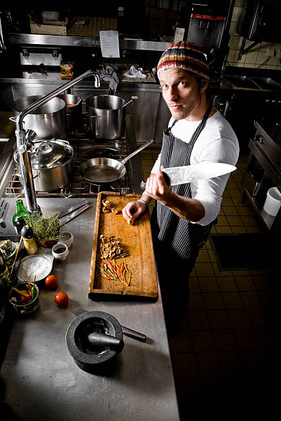 istock Chef Holding Large Knife Standing at Wooden Cutting Board 108178532