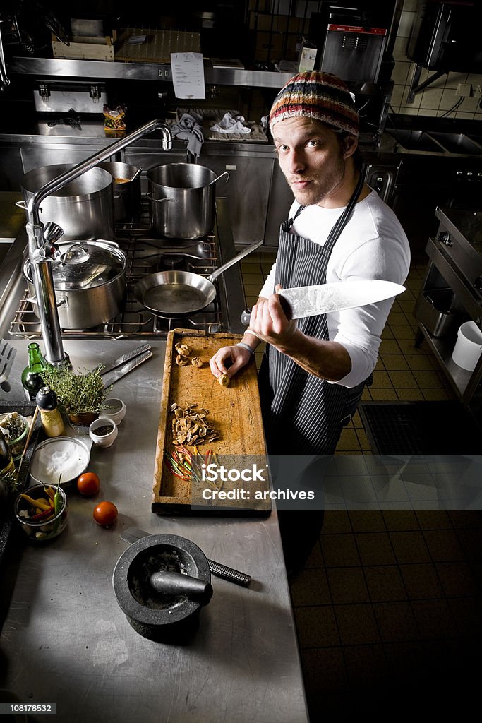 Шеф-повар держит большой нож стоя на Деревянная Разделочная доска - Стоковые фото Повар роялти-фри