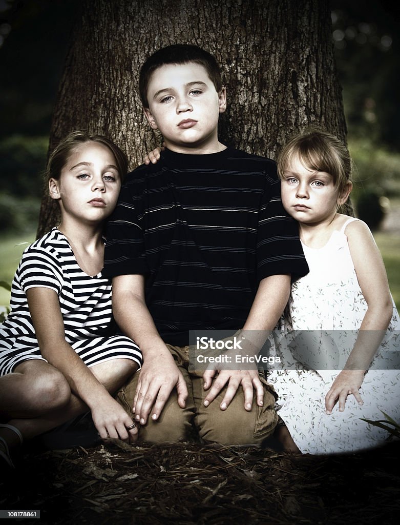 Retrato de tres niños pequeños graves de estar cerca de árbol - Foto de stock de Aire libre libre de derechos