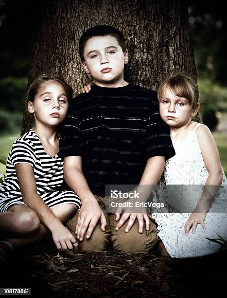 Retrato De Três Graves Pouco Crianças Sentado Perto De Árvore - Fotografias de stock e mais imagens de Amor