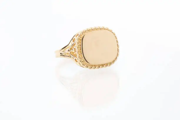 One men's gold bezel ring with plain shiny flat golden surface on white background with reflection
