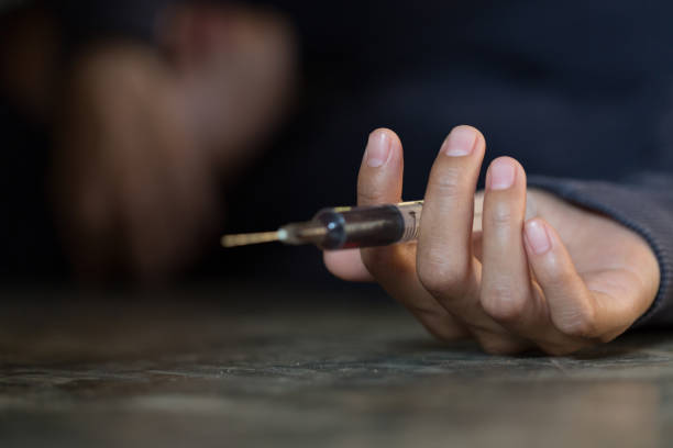 young woman  hand holding a syringe and drug overdose,the concept of crime and drug addiction. 26 june, international day against drug abuse. - narcotic teenager cocaine drug abuse imagens e fotografias de stock