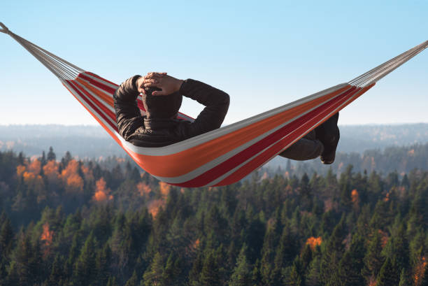 istock A man is lying on a hammock on a hill above a pine forest. His hands behind his head. 1081816244