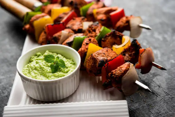 Chicken tikka /skew Kebab. Traditional Indian dish cooked on charcoal and flame, seasoned & colourfully garnished. served with green chutney and salad. selective focus