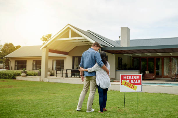 Around the house Shot of a couple standing next to a real estate sold sign at their new house for sale sign photos stock pictures, royalty-free photos & images