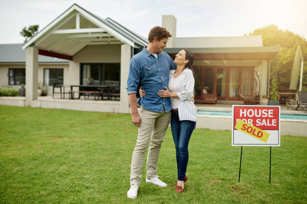 Owning your own house is a good feeling Shot of a couple standing next to a real estate sold sign at their new house house for sale by owner stock pictures, royalty-free photos & images