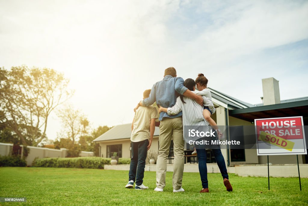 I'm moving my family into our dream home Shot of a family of four viewing their new home together Moving House Stock Photo