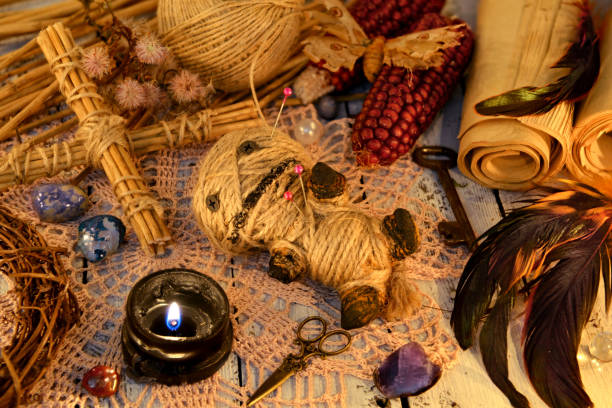 istock Scary voodoo doll with rooster feathers, black candle, cross and paper scrolls on witch table 1081828482