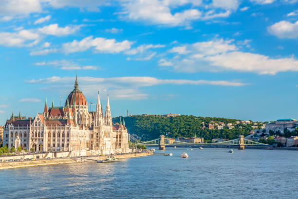 travel and european tourism concept. parliament and riverside in budapest hungary with sightseeing ships during summer sunny day with blue sky and clouds - provincial legislature imagens e fotografias de stock