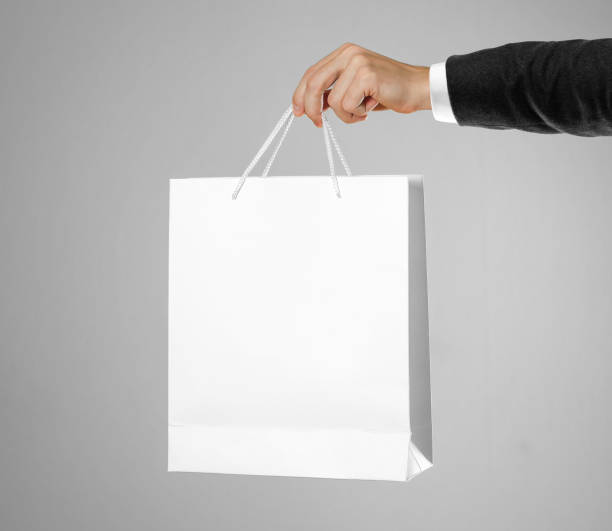 istock Hand in white shirt and black jacket holds a white gift bag 1081847030