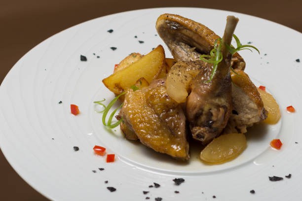 Roasted guinea fowl with potatoes, with green herbs, placed on a white plate Roasted guinea fowl with potatoes, with green herbs, placed on a white plate guinea fowl stock pictures, royalty-free photos & images