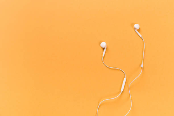 istock White earphones on orange background 1081854034