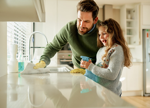 Shot of a father and his little daughter cleaning a kitchen surface together at home