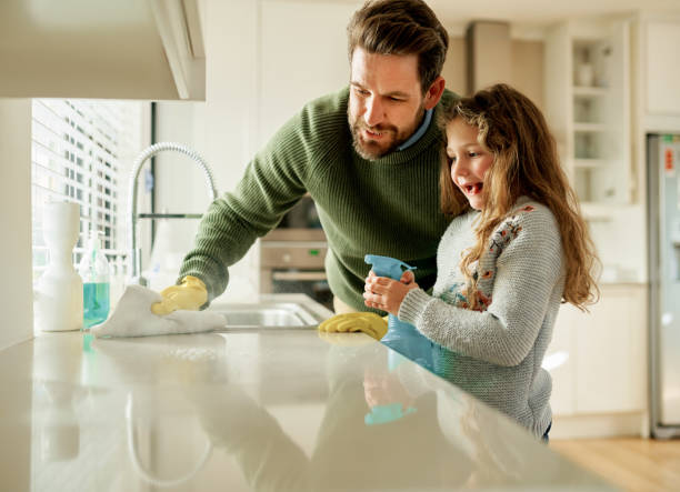 Dad always involves her in household duties Shot of a father and his little daughter cleaning a kitchen surface together at home father housework stock pictures, royalty-free photos & images