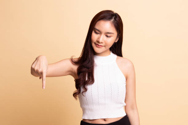 istock Beautiful young Asian woman point down to blank space. 1081860136