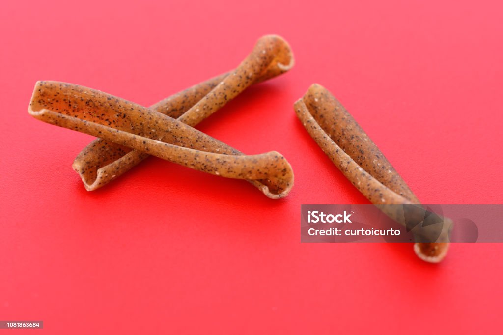 Italian pasta casarecce of legume on red background Brown Stock Photo